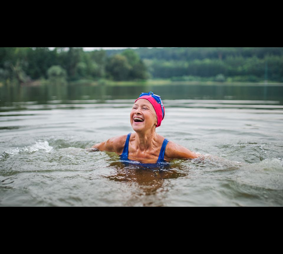 Vrolijke gepensioneerde vrouw in water met badmuts