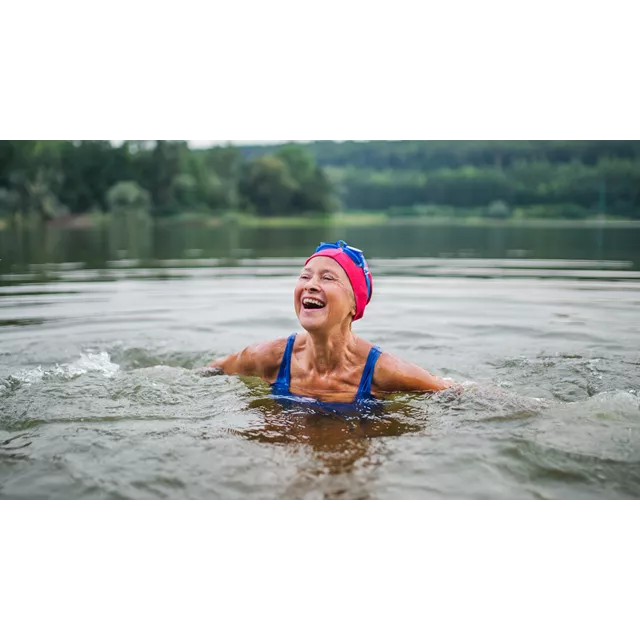 Vrolijke gepensioneerde vrouw in water met badmuts