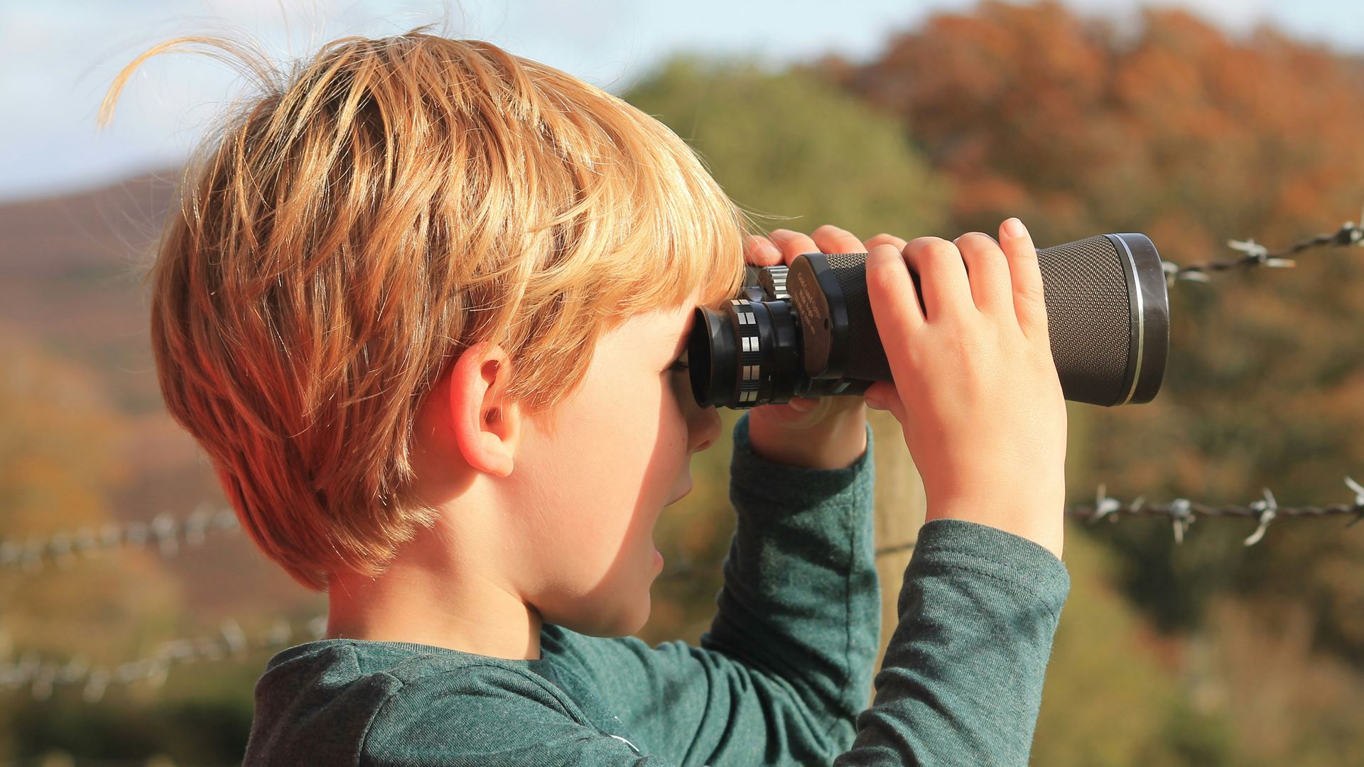 Jongetje met verrekijker kijkend naar rechts