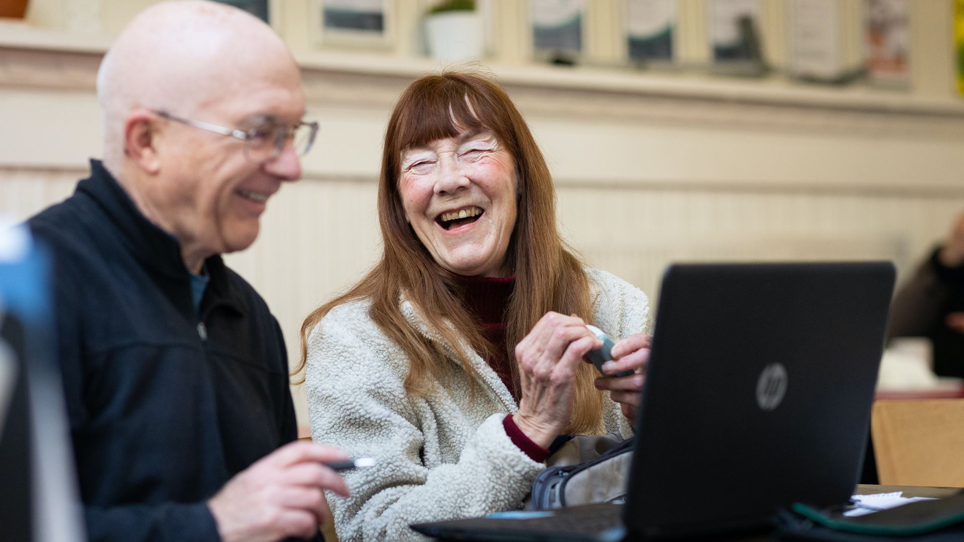 Lachende gepensioneerde vrouw achter laptop