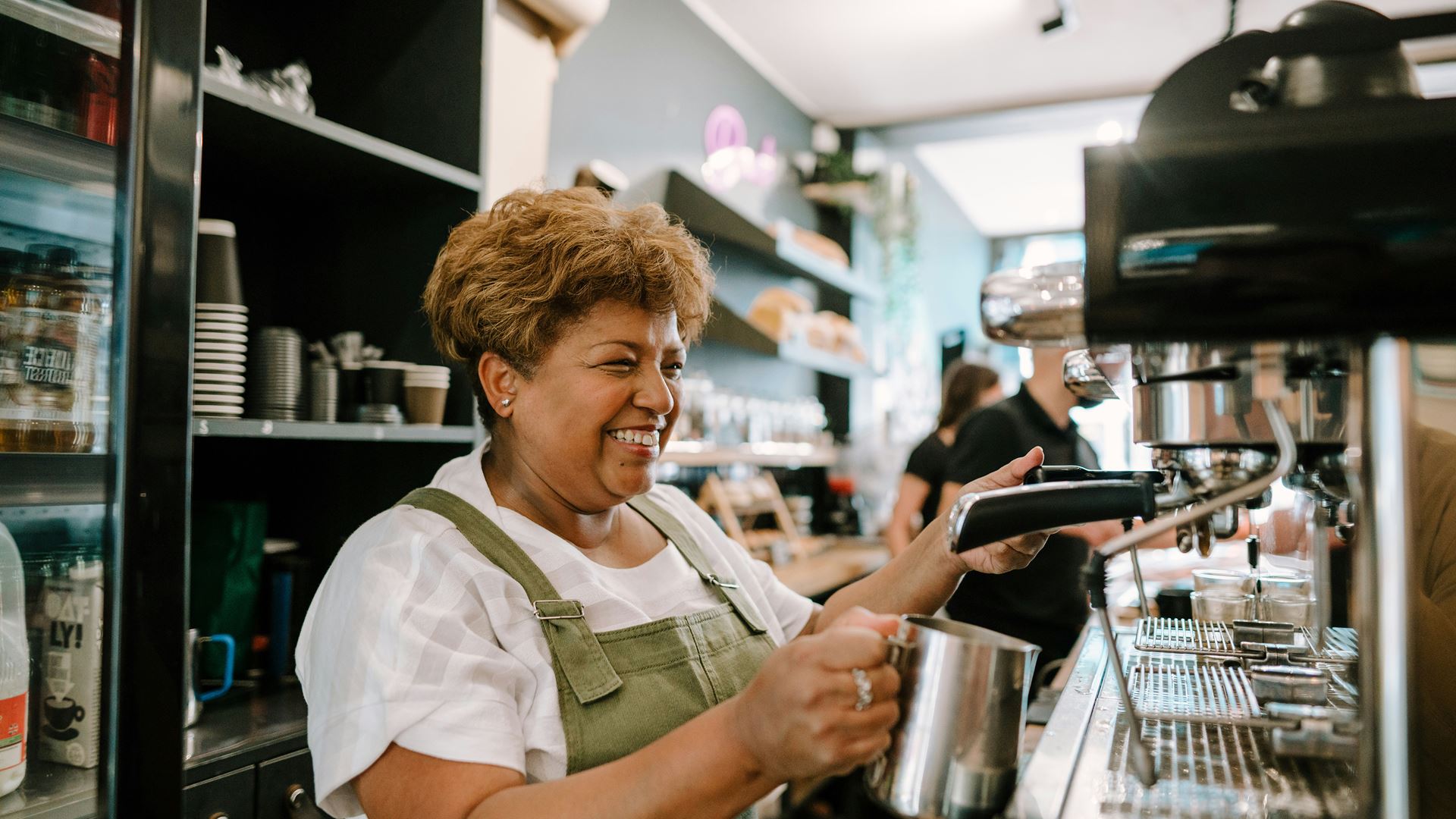 Lachende oudere vrouw bij koffie machine