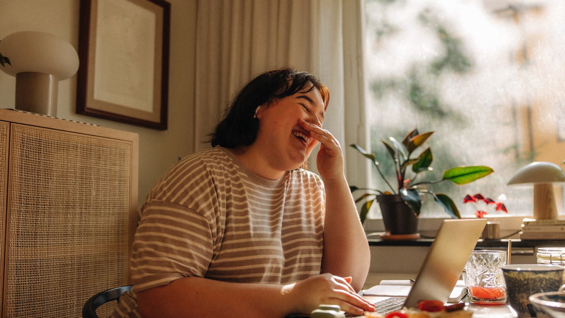 Lachende vrouw aan tafel met laptop