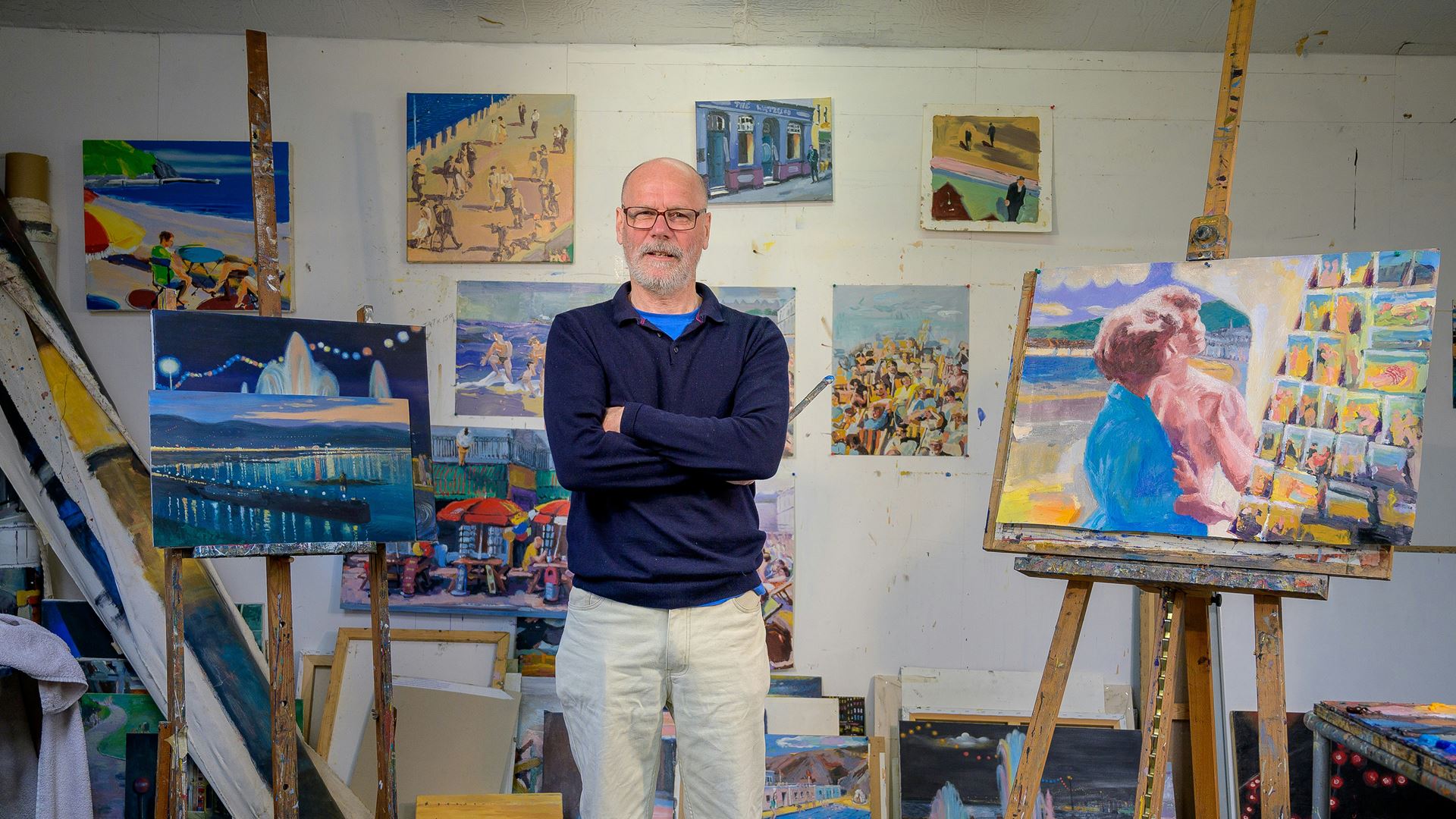 Oudere man trots bij zijn schilderijen